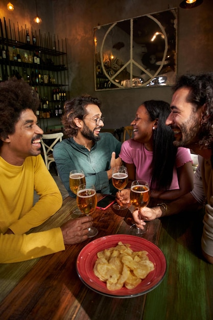 Jóvenes riendo y bebiendo en un pub grupo de amigos celebrando una fiesta juntos