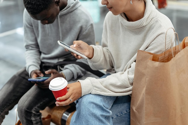 Jóvenes con smartphones y café para llevar sentados en ab