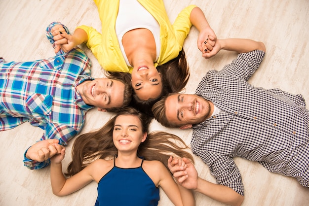 Jóvenes tendidos en el suelo tomados de la mano