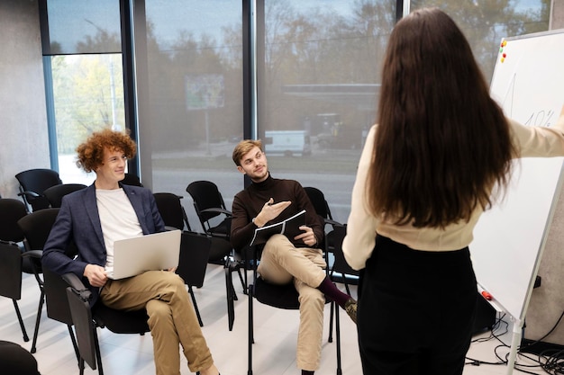 Jóvenes trabajadores atractivos que planean trabajar en una reunión con el gerente Estudiantes atractivos que estudian el maestro explicando