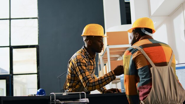 Los jóvenes trabajadores del depósito hacen un cartel de golpe de puño en el almacén, saludándose en el trabajo. Equipo de personas que trabajan en paquetes en estantes y estantes, cajas de mercadería. Disparo de mano.