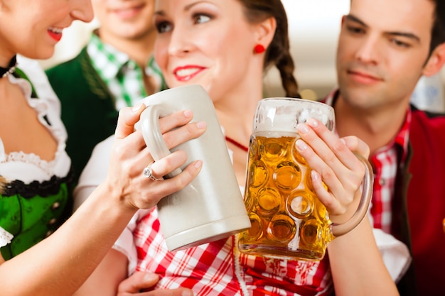 Jóvenes en Tracht tradicional bávara en restaurante o pub