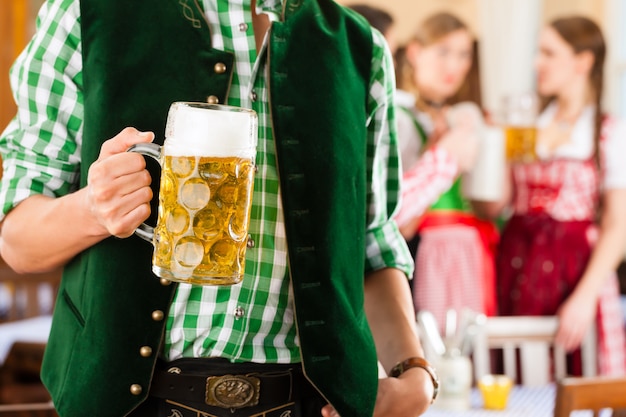 Jóvenes en Tracht tradicional bávara en restaurante o pub
