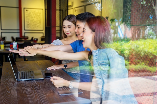 Jóvenes uniendo sus manos con una laptop en un café