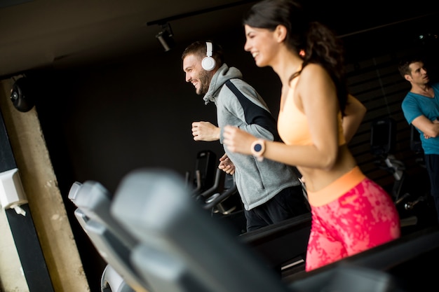 Jóvenes usando threadmill en gimnasio moderno