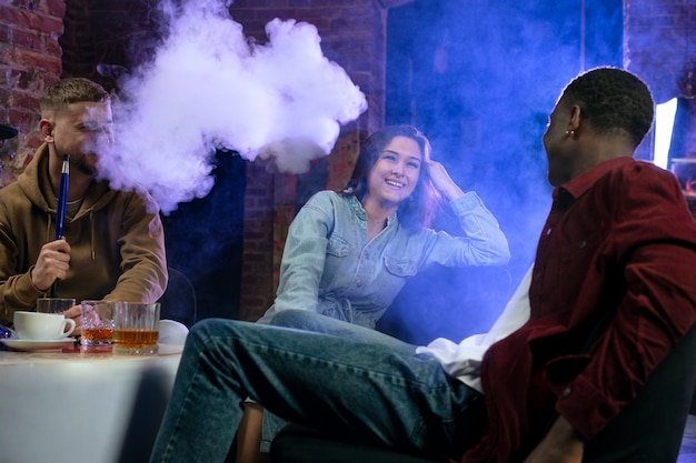 Jóvenes vapeando desde una pipa de agua en un bar.