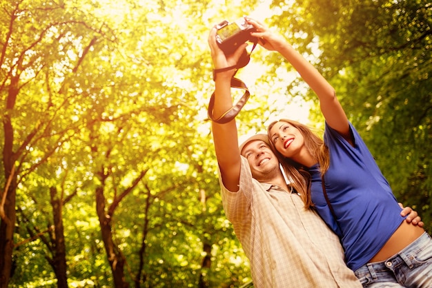 Jóvenes viajeros parados en el bosque y tomando fotos con una cámara digital.