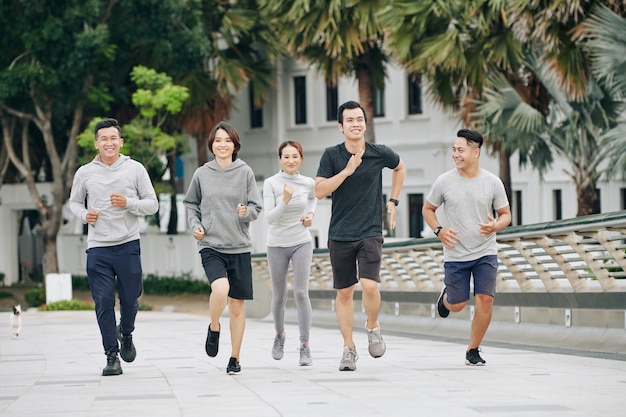 Los jóvenes vietnamitas alegres disfrutan de correr y entrenar juntos en el parque de la ciudad