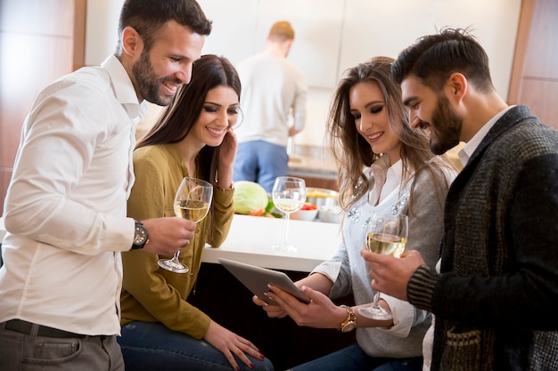 Jóvenes con vino blanco en la cocina.