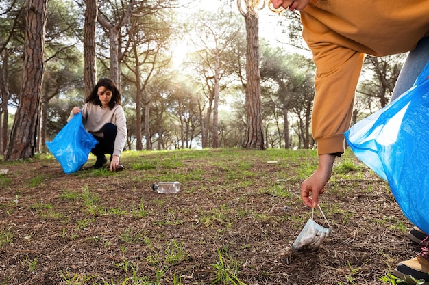 Jóvenes voluntarias recogiendo basura para limpiar el bosque. Copie el espacio. Concepto de activismo ambiental.