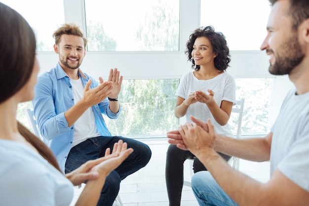 Foto jovens alegres e alegres sorrindo e aplaudindo enquanto mostram seu apoio