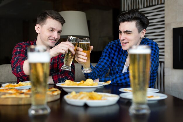 Foto jovens alegres sorriem e comemoram o sucesso enquanto descansam no pub.