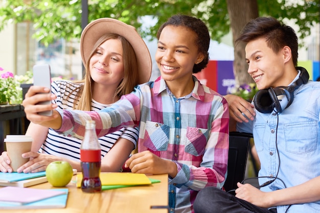 Foto jovens alegres tomando selfie no café