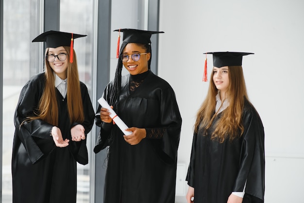 Jovens alunas vestidas com manto comemorando sua formatura