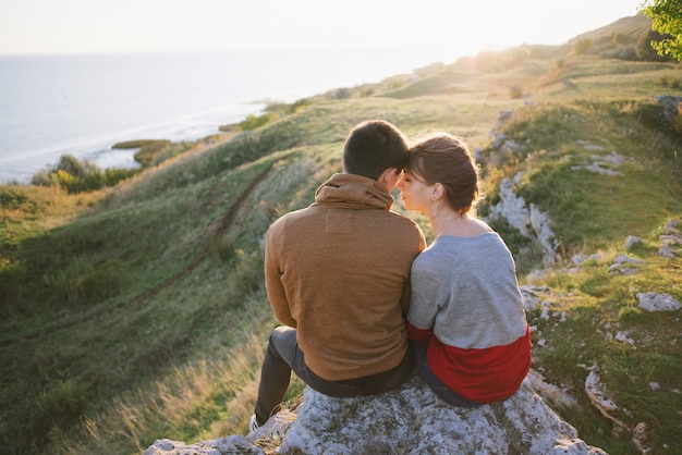 Jovens amantes ao pôr do sol nas montanhas