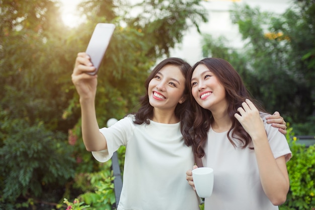 Jovens amigas felizes, bem vestidas e sorrindo juntas