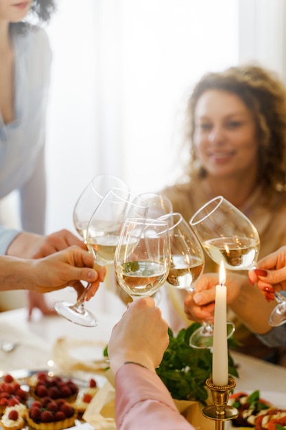 Jovens amigas felizes tilintando copos na mesa festiva decorada com velas