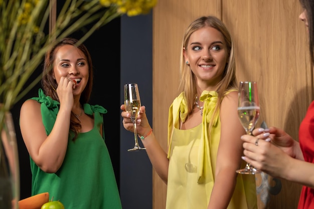 Jovens amigáveis positivas bebendo champanhe e conversando em casa Conceito de festa de despedida de solteiro de amigos de celebração