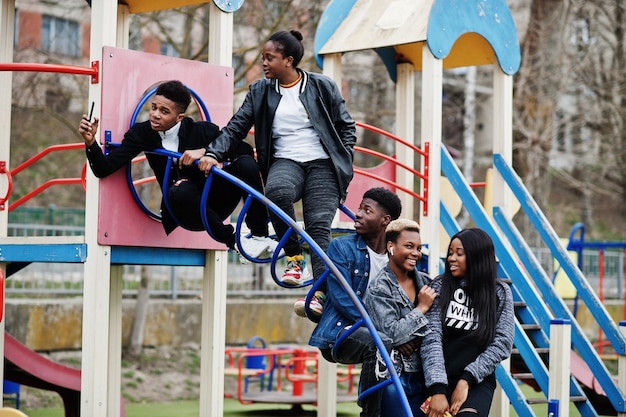 Jovens amigos africanos da geração do milênio no playground deslizam e balançam Pessoas negras felizes se divertindo juntos Conceito de amizade da geração Z