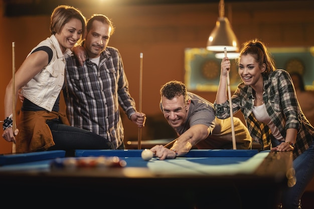 Foto jovens amigos alegres estão jogando bilhar no bar depois do trabalho. um casal que ganha fama e os perdedores estão de mau humor.