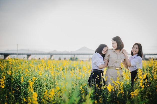 Jovens amigos asiáticos em um campo de flores de crotalária