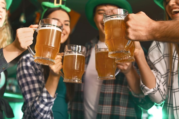 Foto jovens amigos com cerveja comemorando o dia de são patrício em bar