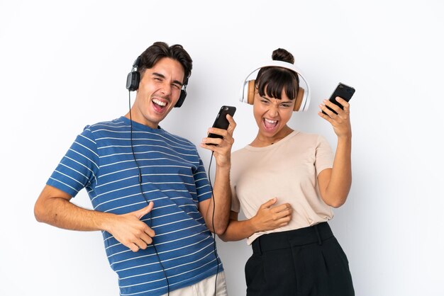 Jovens amigos de raça mista isolados em fundo branco ouvindo música e fazendo gesto de guitarra