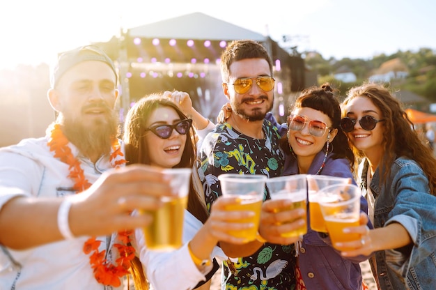 Jovens amigos felizes bebendo cerveja e se divertindo juntos no festival de música Amizade