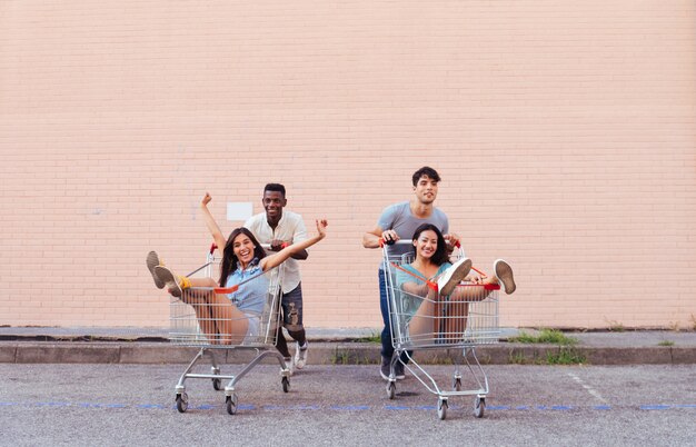 Jovens amigos felizes correndo com carrinhos de compras