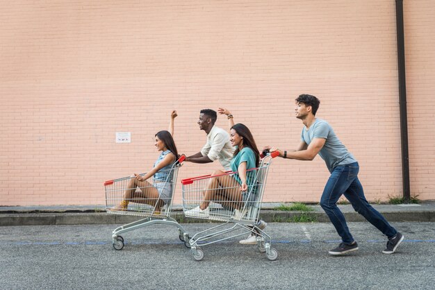 Jovens amigos felizes correndo com carrinhos de compras