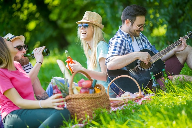 Jovens amigos felizes fazendo piquenique no parque