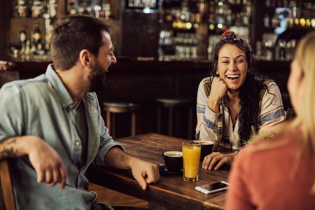 Jovens amigos felizes se divertindo enquanto conversavam em um café