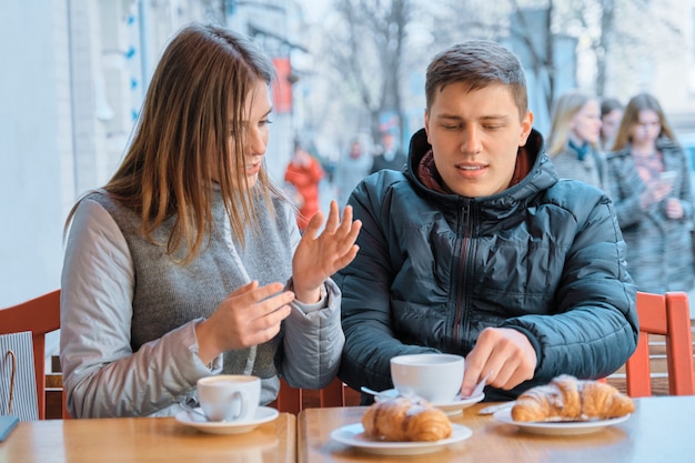 Jovens amigos homem e mulher conversando no café ao ar livre