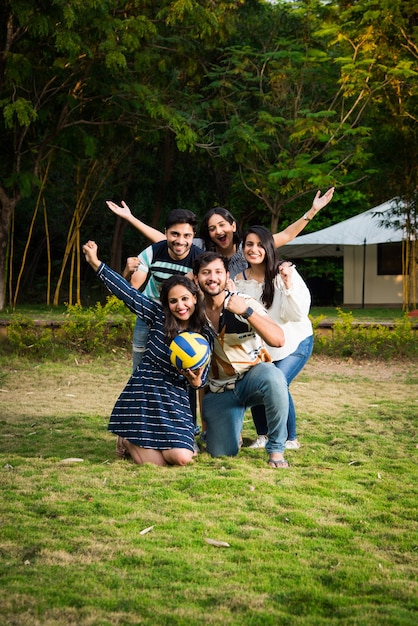 Jovens amigos indianos asiáticos jogando futebol, futebol ou vôlei e torcendo