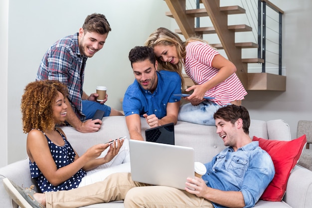 Jovens amigos olhando no laptop enquanto está sentado no sofá