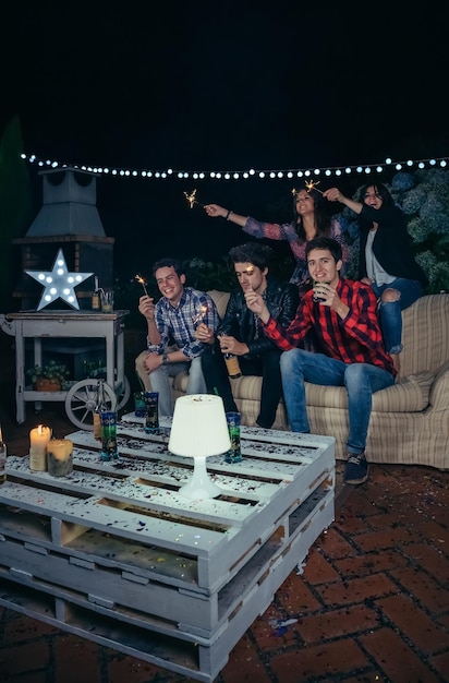 Foto jovens amigos segurando faíscas durante uma festa no quintal à noite