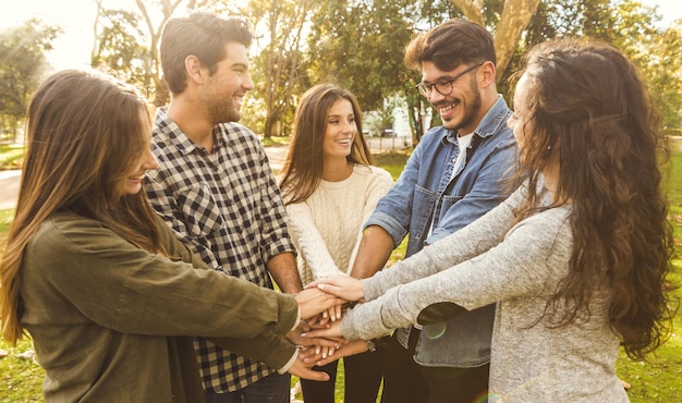 Foto jovens amigos sorridente empilhando as mãos no parque