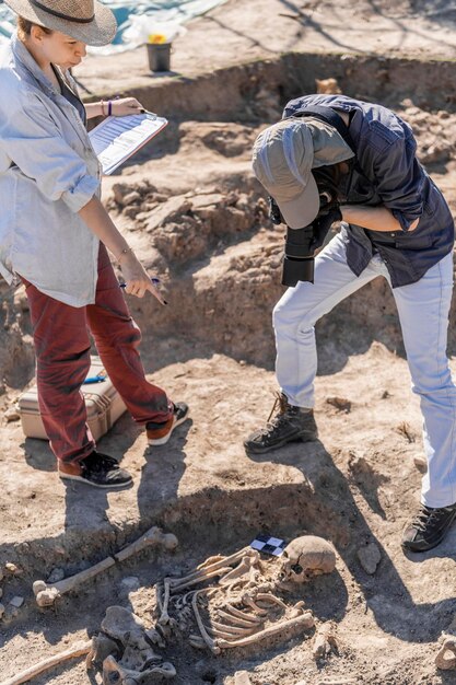 Foto jovens arqueólogos documentando um antigo local de sepultamento com uma câmera