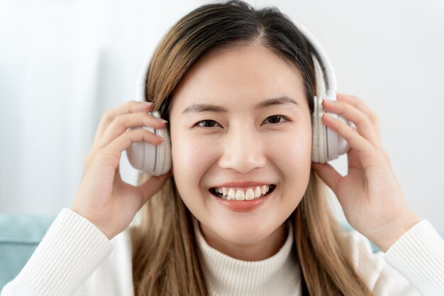 Foto jovens asiáticas alegres em fones de ouvido sem fio sentadas e curtindo música se divertindo ouvindo música levantando o braço dançando a música favorita desfrutando de uma trilha sonora legal recreação de vida feliz