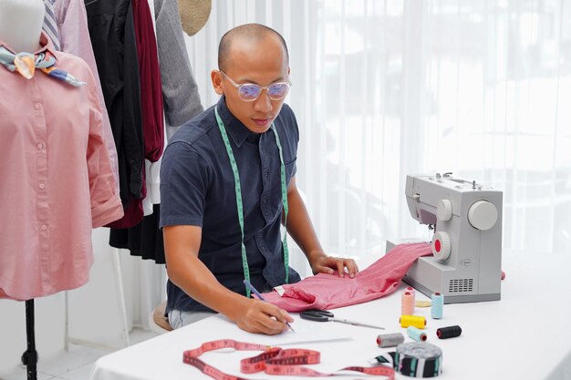 jovens asiáticos concentrados designer de moda sentado em sua oficina trabalhando na nova coleção