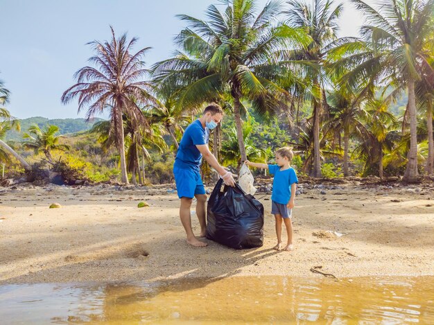 Jovens ativistas familiares felizes coletando resíduos plásticos na praia Pai e filho voluntários limpam lixo Problemas de poluição ambiental Recreação de estilo de vida ao ar livre Educação natural das crianças