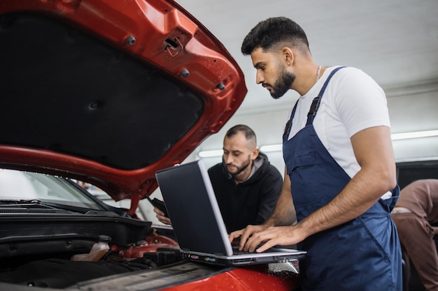 Foto jovens barbudos colegas mecânicos de automóveis reparando o problema do motor do carro