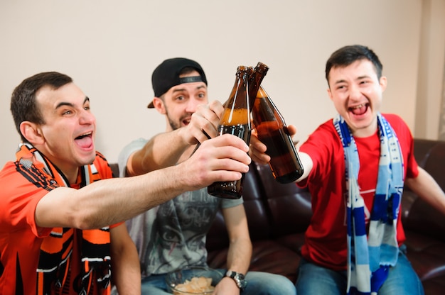 Jovens bebem cerveja, comem batata frita e torram para futebol