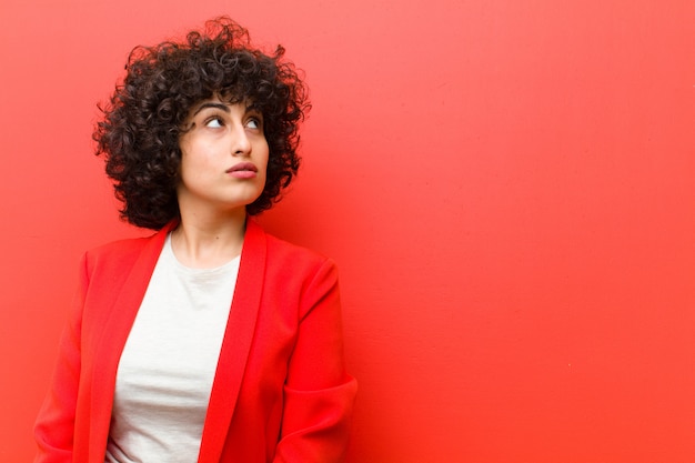 Jovens bonitas mulher afro com uma expressão preocupada, confusa, sem noção, olhando para copiar o espaço, duvidando