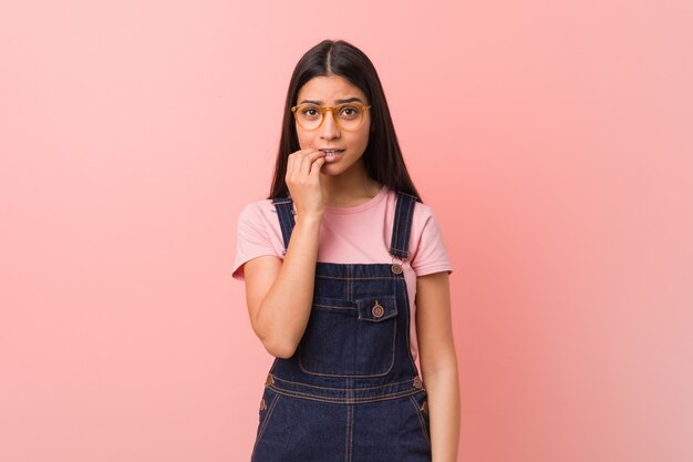 Jovens bonitas mulher árabe vestindo um jeans dungaree roer unhas, nervoso e muito ansioso.