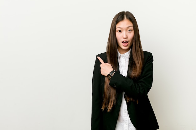 Jovens bonitas mulher de negócios chinês apontando para o lado