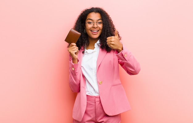 Jovens bonitas mulher de negócios com uma carteira contra parede rosa