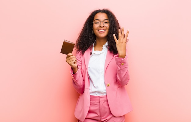 Jovens bonitas mulher de negócios com uma carteira contra parede rosa