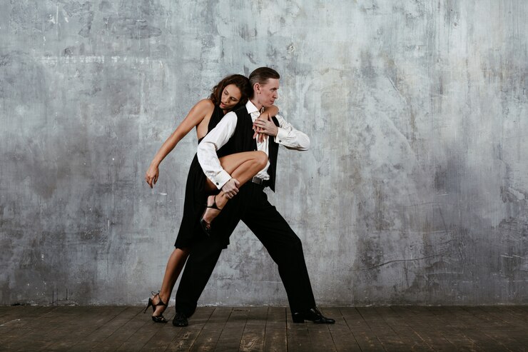 Foto jovens bonitas mulher de vestido preto e homem dançando tango
