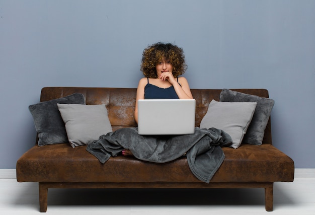 Jovens bonitas mulher em casa, sentado em um sofá com um laptop